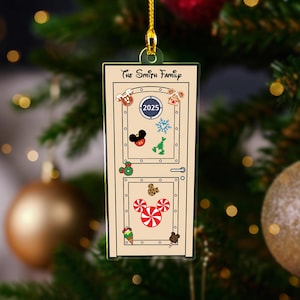 May include: A door-shaped Christmas ornament with the text "The Smith Family" at the top. The door is decorated with festive images such as gingerbread men, Mickey Mouse, and candy canes. The year "2025" is displayed on the ornament.