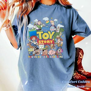 Puede incluir: Una camiseta azul de manga corta con un estampado gr&aacute;fico colorido de varios personajes de Toy Story, incluyendo a Woody, Buzz Lightyear y Jessie. El texto "TOY STORY" y "YOU'VE GOT A FRIEND IN ME" est&aacute; impreso en una fuente negrita multicolor.