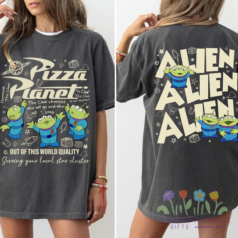 May include: Dark gray t-shirt with a Pizza Planet graphic on the front and Alien characters on the back. The front features the Pizza Planet logo and alien characters. The back has the word "Alien" repeated.