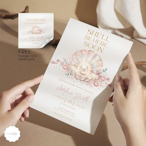 Puede incluir: Una invitación para baby shower con un diseño de perla y concha. La invitación incluye el texto "She'll Be Here Soon" y "Join us for a Baby Shower Honoring Adeline Smith". También se incluye una tarjeta de agradecimiento a juego.