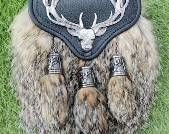 May include: A black leather sporran with a silver stag head and antlers design. The sporran has three brown fur tassels with silver bells.