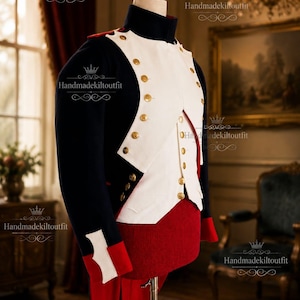 May include: A dark navy blue military-style tailcoat featuring a white chest panel, gold-toned buttons, and red accents on the cuffs and lower section. The garment is displayed on a mannequin and includes the text Handmadekiltoutfit.