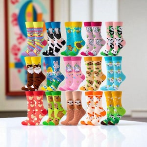 Puede incluir: Una colección de calcetines coloridos con varios diseños de animales y naturaleza. Los calcetines presentan imágenes de gatos, vacas, pandas, perezosos, zorros y más. Los calcetines se muestran en filas, mostrando la variedad de patrones y colores.
