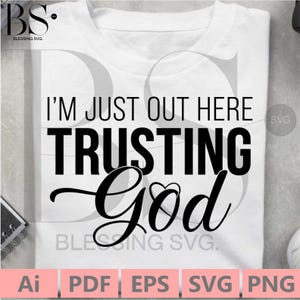 May include: A white t-shirt with black text that reads "I'm just out here trusting God" with a heart symbol in the word "God".