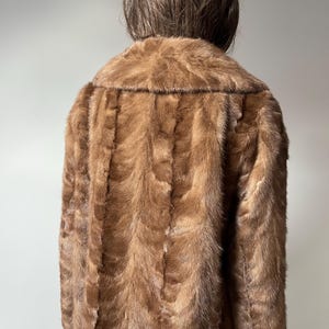 Pu&ograve; includere: Un cappotto di pelliccia marrone con un ampio colletto. Il cappotto &egrave; realizzato in un materiale morbido e strutturato e ha un design classico. Il cappotto &egrave; di colore marrone medio e sembra in buone condizioni.