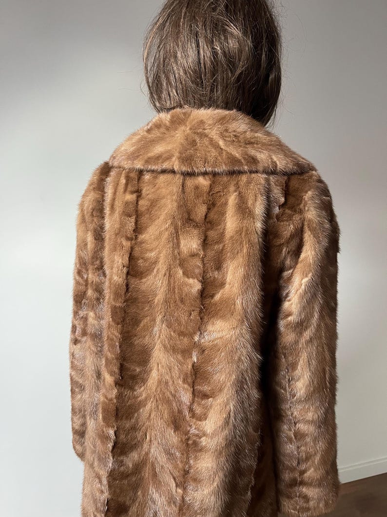 Pu&ograve; includere: Un cappotto di pelliccia marrone con un ampio colletto. Il cappotto &egrave; realizzato in un materiale morbido e strutturato e ha un design classico. Il cappotto &egrave; di colore marrone medio e sembra in buone condizioni.
