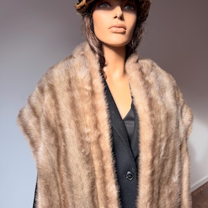 Pode incluir: Um manequim vestindo uma estola de pele vintage e um chap&eacute;u com estampa de leopardo. A estola de pele &eacute; marrom claro e cobre um blazer preto. O chap&eacute;u tem uma fita marrom e um padr&atilde;o de leopardo.