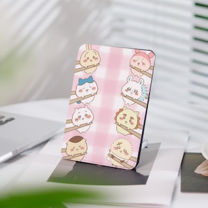 Könnte beinhalten: Eine rosa und weiße Handyhülle mit einem karierten Muster und Comic-Tieren, die Essstäbchen halten. Die Tiere sind weiß mit verschiedenen farbigen Akzenten, darunter Blau, Rosa und Gelb.