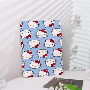 Könnte beinhalten: Eine blaue und weiße Hülle mit einem sich wiederholenden Muster von Hello Kitty-Gesichtern. Die Hülle hat einen weißen Rand und ist aus hartem Kunststoff.