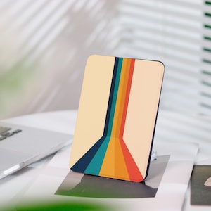 Könnte beinhalten: Rechteckige Handyhülle mit Retro-Design. Die Hülle hat einen cremefarbenen Hintergrund mit einer Reihe farbiger Streifen in Marine, Türkis, Orange und Rot. Die Streifen konvergieren zum unteren Rand der Hülle und erzeugen einen visuellen Effekt.