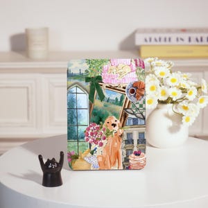 Peut inclure: Panneau décoratif rectangulaire avec une illustration à l'aquarelle d'un golden retriever tenant des fleurs, une fenêtre et un tableau encadré. Le panneau a un nœud vert et des crêpes.