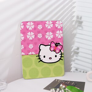 Könnte beinhalten: Eine rosa und grüne Hülle mit einem Hello-Kitty-Design. Die Hülle zeigt ein weißes Hello-Kitty-Gesicht mit einem rosa Schmetterling auf dem Kopf. Der Hintergrund ist ein rosa und weißes Blumenmuster mit grünen Punkten.