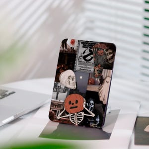 Könnte beinhalten: Eine Handyhülle mit einem Halloween-Collage-Design. Die Bilder zeigen einen Schädel, ein Skelett mit Kürbiskopf, einen Geist und ein Vintage-Filmposter. Die Hülle hat eine dunkle Farbgebung mit einem glänzenden Finish.
