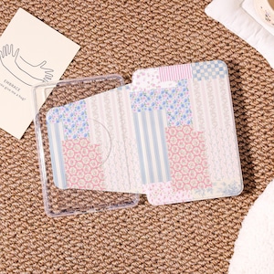 Peut inclure: Coque de téléphone transparente avec un motif patchwork à fleurs et rayures roses, bleues et blanches. Une carte avec le mot "EMBRACE" et la phrase "you give me a hug?" est visible.