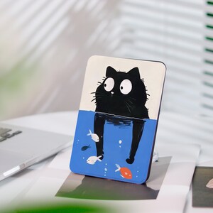 Könnte beinhalten: Handyhülle mit einer Illustration einer schwarzen Katze im blauen Wasser, mit Fischen. Die Katze hat große Augen. Der obere Teil der Hülle ist weiß. Das Design ist verspielt und farbenfroh.