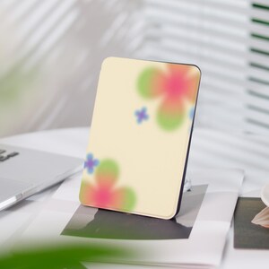 Könnte beinhalten: Eine gelbe E-Reader-Hülle mit einem Blumendesign. Die Blumen sind rosa, grün und blau.