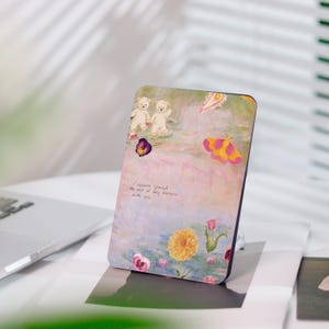 Könnte beinhalten: Eine rechteckige Handyhülle mit einem pastellfarbenen Blumen- und Bären-Design. Das Kunstwerk zeigt zwei weiße Teddybären, gelbe und rosa Blumen sowie einen rosa und gelben Schmetterling. Der Text "I wanna spend the rest of my summers with you" ist ebenfalls sichtbar.