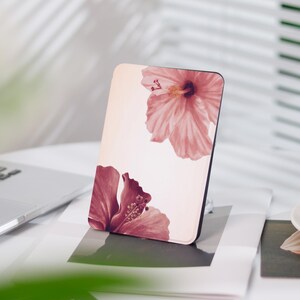 Könnte beinhalten: Eine rosa-weiße E-Reader-Hülle mit einem Blumendesign mit zwei Hibiskusblüten. Die Blüten sind rosa und rot auf weißem Hintergrund.