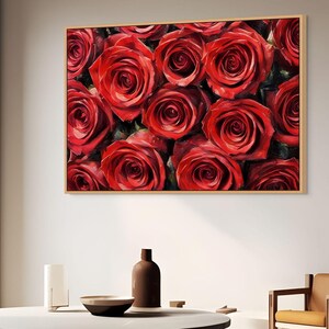 May include: A framed artwork featuring a close-up of numerous vibrant red roses. The roses are densely packed, showcasing their layered petals and rich color. The artwork is set in a light-colored wooden frame, adding a touch of warmth.
