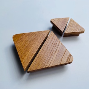 Può includere: Quattro sottobicchieri triangolari in legno con angoli arrotondati. I sottobicchieri sono realizzati in legno marrone chiaro e presentano un motivo a venature visibili. Due sottobicchieri sono uniti e due sono separati.