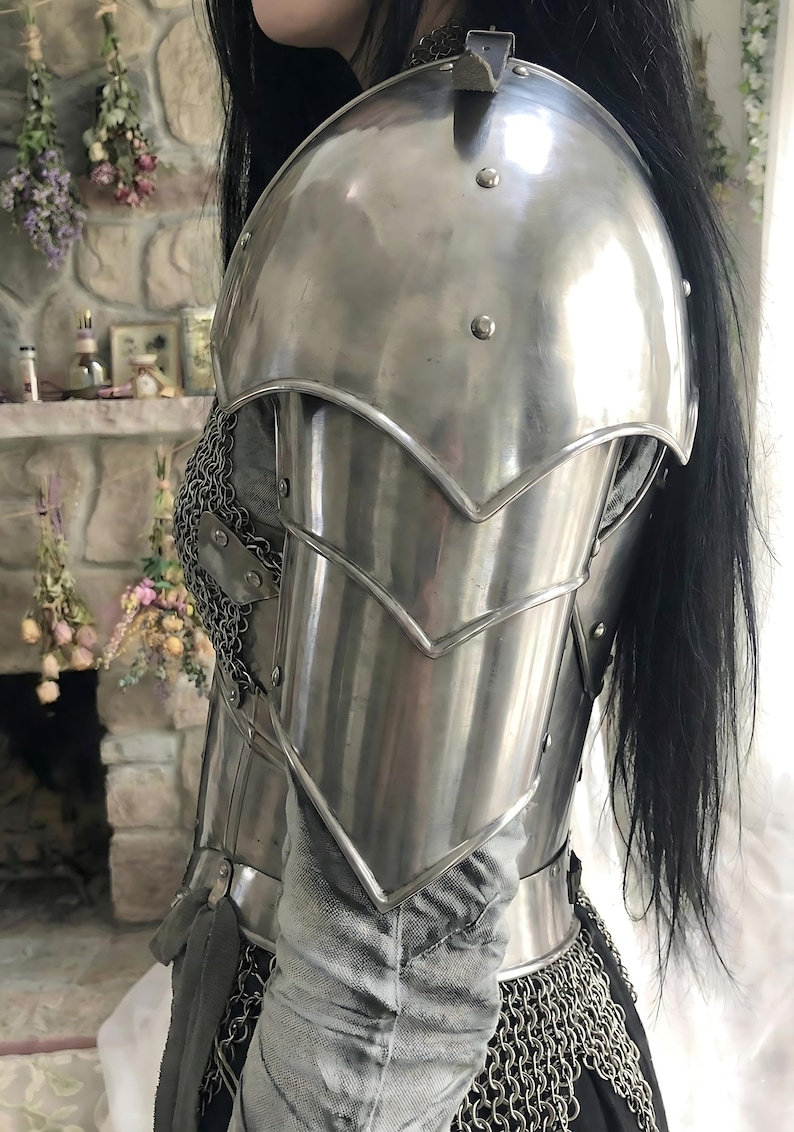 May include: Polished steel shoulder armor with riveted accents and a layered design. The armor features a curved shoulder plate and articulated arm protection, with chainmail visible at the edges. A medieval-themed product.