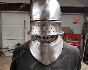 Könnte beinhalten: Ein polierter mittelalterlicher Helm aus Stahl mit Visier und Nackenschutz. Der Helm dient zum Schutz von Kopf und Nacken. Das Visier hat mehrere kleine Löcher zur Belüftung. Der Helm wird auf einem schwarzen T-Shirt präsentiert.