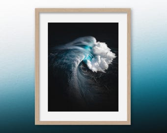 May include: A framed photograph of a large wave breaking in the ocean. The wave is backlit by the sun, creating a bright blue glow. The water is dark blue and the sky is black.