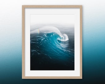 May include: A large, powerful wave breaks in the ocean, creating a dramatic, swirling pattern of blue and white water.