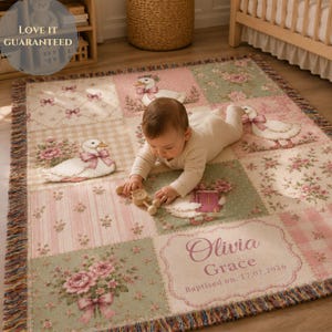 Può includere: Una coperta tessuta con un design patchwork che presenta illustrazioni di anatre bianche con fiocchi rosa, motivi floreali e quadrati a quadretti rosa. La coperta include il testo Olivia Grace e la data Baptised on 17.07.2026.