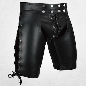 Puede incluir: Pantalones cortos de cuero negro con cordones en la parte delantera y laterales. Los pantalones cortos tienen cierre de botón en la cintura y cremallera lateral. Diseño de corte tipo chaps.