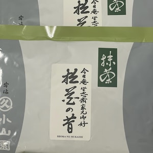 May include: Two matcha tea packages with Japanese text on white labels and green borders. The text "SHOKA NO MUKASHI" is printed on the label. The brand name "MARUKYU KOYAMAEN" is printed at the bottom of the packages.