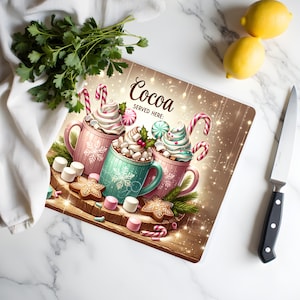 May include: A decorative chopping board with three mugs of hot chocolate, topped with whipped cream, candy canes, and marshmallows. The board reads "Cocoa SERVED HERE:" and is surrounded by gingerbread biscuits and sweets. Lemons, parsley, and a knife are also present.