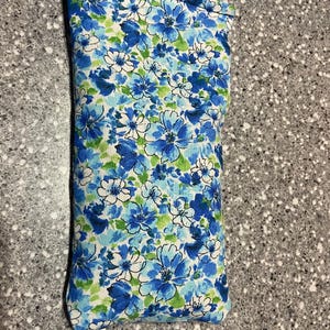 May include: A blue and white floral print eye pillow. The pillow is rectangular and has a seam down the centre.