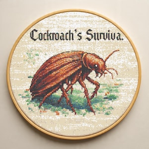 May include: A cross-stitch embroidery in a wooden hoop features a detailed brown cockroach with the text "Cockroach's Surviva." The insect is set against a background of light green and beige, creating a unique piece of art.