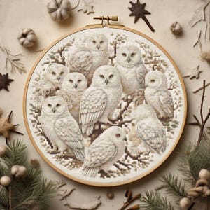 Peut inclure: Un cercle de broderie circulaire avec un fond blanc et un motif d'un groupe de hiboux blancs perchés sur des branches. Les hiboux sont entourés de branches et de feuilles brunes.