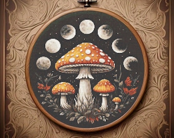 May include: Cross-stitch art featuring a large orange mushroom with white spots, surrounded by smaller mushrooms and phases of the moon. The artwork is set in a wooden embroidery hoop and framed with a decorative border.
