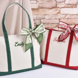 May include: Two canvas tote bags, one white with green trim and the name "Emily" embroidered in green, the other white with red trim and the name "Sophia" embroidered in red. Both bags have decorative bows.
