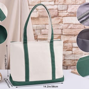 May include: A white canvas tote bag with green detailing. The bag features green trim and handles. It measures 36cm wide, 29cm high, and 14cm deep. The bag has a zip closure and a lined interior. Ideal for everyday use.