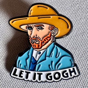 May include: A colorful enamel pin featuring a portrait of Vincent van Gogh wearing a yellow hat and blue jacket. The pin has the phrase "LET IT GOGH" in white letters on a black background.