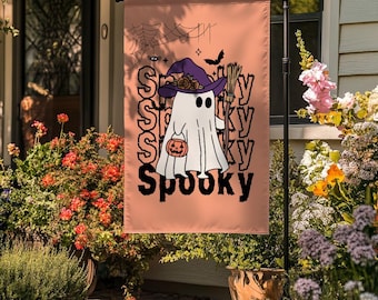 May include: A Halloween garden flag with a ghost wearing a witch hat and holding a pumpkin bucket. The flag has the word "Spooky" in a stylized font, along with a spiderweb and a bat. The background is a light orange color.