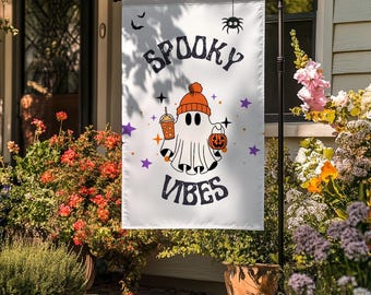 May include: A white Halloween garden flag with the words "Spooky Vibes" and a cartoon ghost wearing an orange beanie, holding a pumpkin and a drink. The flag also features a spider, bats, and stars.