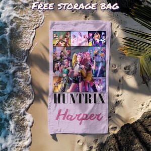 May include: A light purple beach towel with a collage of images and the text "HUNTRIX Harper". The towel is lying on a sandy beach with the text "FREE STORAGE BAG" at the top. The towel is rectangular and appears to be made of a soft material.