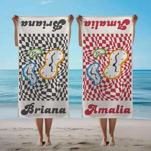 May include: Two beach towels with unique designs. One features a black and white checkered pattern with melting clocks and the name "Briana". The other has a red and white checkered pattern with melting clocks and the name "Amalia".