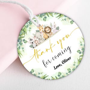 May include: Circular gift tag featuring a watercolour illustration of safari animals, such as a giraffe, lion, and elephant. The tag has the text "Thank you for coming" in gold script, with "Love, Oliver" below.