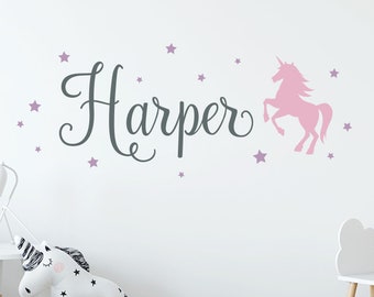 May include: A pink unicorn silhouette with a grey name "Harper" and purple stars on a white wall.