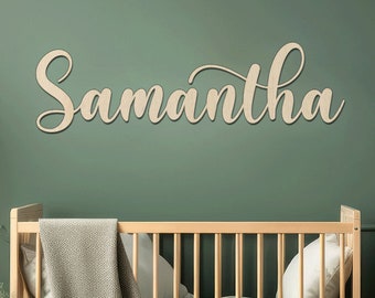 May include: A wooden name sign with the name "Samantha" written in a cursive font. The sign is mounted on a green wall above a wooden crib.
