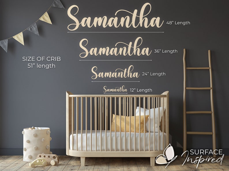 May include: A nursery room with a white crib, a white pom-pom storage bin, and a wooden ladder. The wall is gray and has a wooden sign with the name "Samantha" written in cursive. The sign is shown in four different sizes: 12 inches, 24 inches, 36 inches, and 48 inches. The text "SIZE OF CRIB 51" length" is also on the wall. The text "SURFACE Inspired" is on the floor.