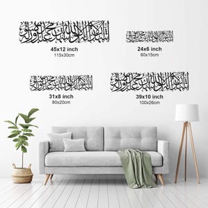 May include: Black Islamic calligraphy wall art in four sizes: 45x12 inch (115x30cm), 24x6 inch (60x15cm), 31x8 inch (80x20cm), and 39x10 inch (100x26cm). The art is displayed above a gray sofa with a green blanket and a floor lamp.