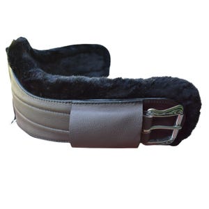 Peut inclure: Une sangle de cheval en cuir marron avec une doublure en peau de mouton noire. La sangle comporte une sangle en cuir marron avec une boucle argentée. La conception comprend des détails cousus et est conçue pour un usage équestre.