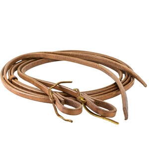 May include: A pair of brown leather reins with brass hardware. The reins are coiled and ready for use.